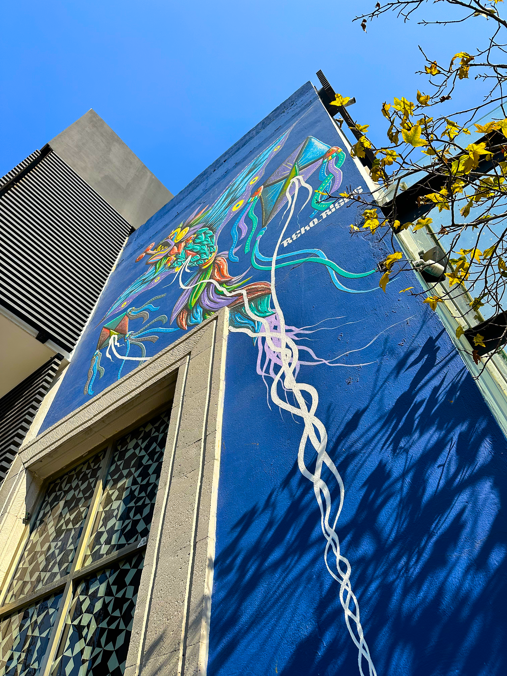 Mural de árbol y raíces en fachada estrecha