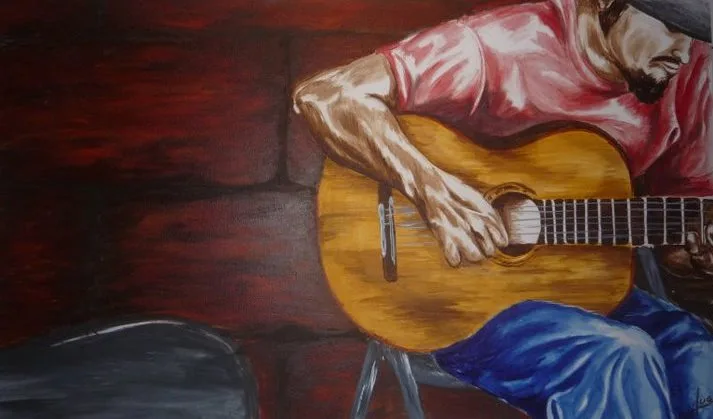 Seated man in red shirt playing acoustic guitar against dark