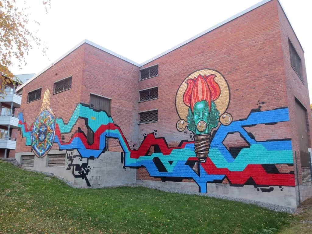 IMG 7248. Mural urbano que combina elementos surreais com formas geométricas e cores vibrantes, destacando um rosto humano fundido com uma flor dentro