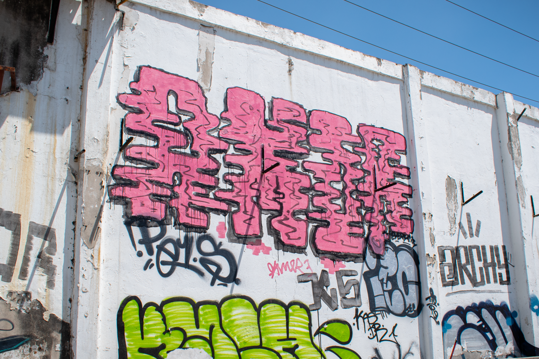 amor al roller. Un vibrante mural de graffiti con letras grandes en tonos rosa y negro sobre una pared de concreto. La obra destaca por su estilo tipo
