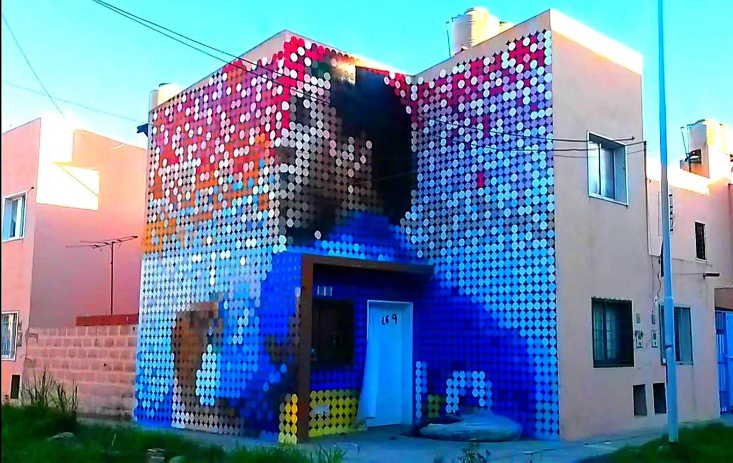 Jugador del pueblo.. Um mural vibrante que representa uma pessoa através de um padrão de pontos coloridos. A obra transforma a fachada de um edifício